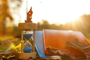 otoño hora tema, reloj de arena en caído hojas en varios colores con Copiar espacio. foto