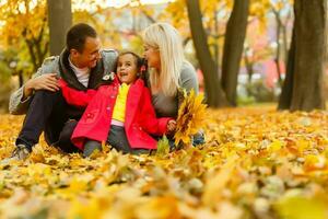 contento familia es sentado en hermosa otoño parque foto