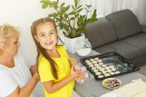 little girl makes cookies from the dough in the kitchen at home photo