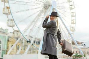 The young girl walks around the city near sights. Ferris wheel. Amusement park. autumn photo