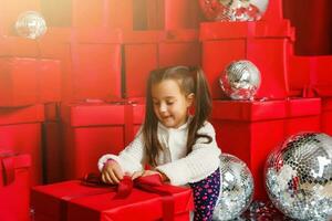 Cheerful cute little child girl with present. Little girl is among the Christmas gifts. photo