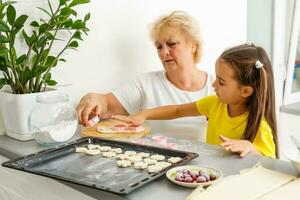 little girl makes cookies from the dough in the kitchen at home photo