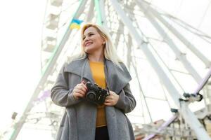 The young girl walks around the city near sights. Ferris wheel. Amusement park. autumn photo