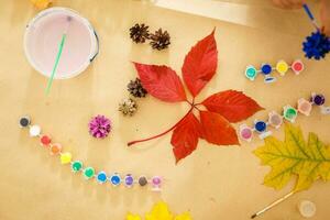 linda pequeño niña colorante un natural cono abeto a crear un flor, conjunto de cepillos, pinturas, natural otoño materiales, crear divertido y fácil con niños, bricolaje para jardín de infancia foto