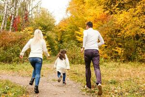 Picture of lovely family in autumn park, young parents with nice adorable daughter playing outdoors, have fun on backyard in fall, happy family enjoy autumnal nature photo