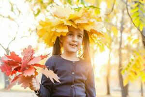 otoño temporada ocio. atmósfera de otoño. adorable sonriente Chica de escuela otoño follaje antecedentes. bueno humor. contento niño. Bienvenido octubre. unido con naturaleza. pequeño niño caminar en otoño parque. foto