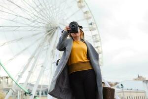 The young girl walks around the city near sights. Ferris wheel. Amusement park. autumn photo