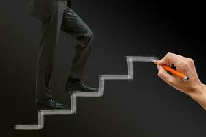 Businessman climbing the career stairs drawn on a chalkboard with copy space photo