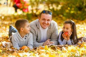 Happy family of three lying in the grass in autumn. Warm effect added. photo