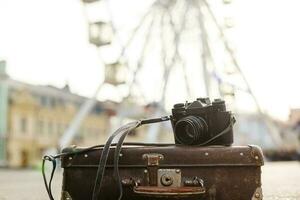 old camera and suitcase against the background of the ferris wheel photo