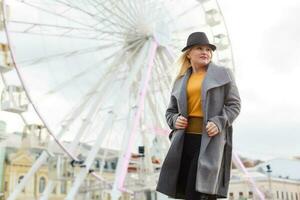 The young girl walks around the city near sights. Ferris wheel. Amusement park. autumn photo