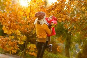 portrait of a young woman and her daughter in the autumn park photo