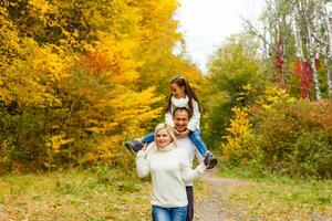 Picture of lovely family in autumn park, young parents with nice adorable daughter playing outdoors, have fun on backyard in fall, happy family enjoy autumnal nature photo