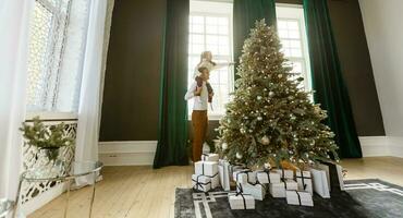 contento joven padre y su hija a hogar con Navidad árbol foto