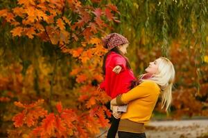 Hello autumn. smiling young mother and daughter in hat outdoors in the city park in autumn having fun time photo