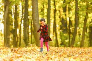 hermosa pequeño niña con otoño hojas al aire libre foto