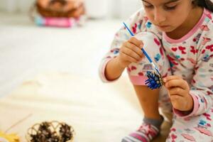 Cute little girl coloring a natural cone fir to create a flower, set of brushes, paints, natural autumn materials, create fun and easy with children, diy for kindergarten photo