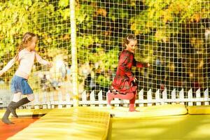 pequeño muchachas teniendo divertido como ellos saltar en trampolín foto