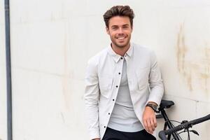 imagen de joven africano hombre con bicicleta en pie terminado blanco pared al aire libre mirando cámara. generativo ai foto