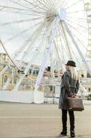 The young girl walks around the city near sights. Ferris wheel. Amusement park. autumn photo