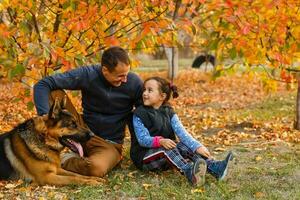 Young family with a dog in leaves on an autumns day photo