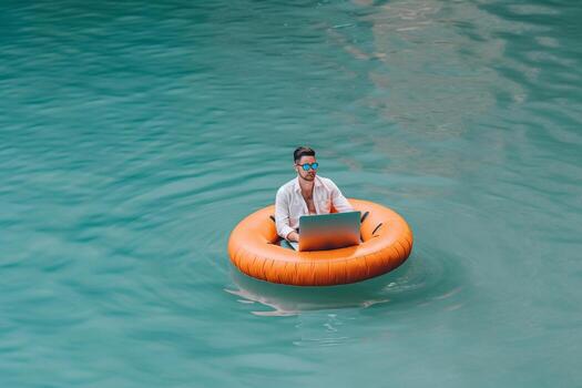 Businessman using laptop computer on an inflatable donut in the sea. Summer vacation concept. photo
