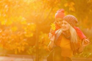 Mother giving daughter piggyback ride in autumn woodland photo