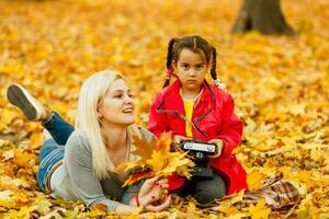 contento familia madre y niño hija jugando y riendo en otoño caminar. foto