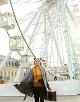 The young girl walks around the city near sights. Ferris wheel. Amusement park. autumn photo