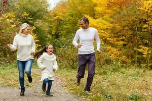 Picture of lovely family in autumn park, young parents with nice adorable daughter playing outdoors, have fun on backyard in fall, happy family enjoy autumnal nature photo