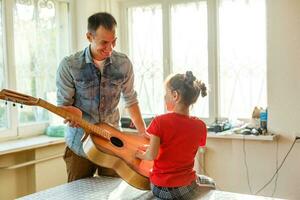 de cerca del hombre mano cambiando instrumentos de cuerda en su antiguo acústico guitarra. foto