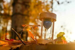 otoño hora tema, reloj de arena en caído hojas en varios colores con Copiar espacio. foto