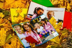 school photo book on the yellow leaves top view. rustick photo of autumn composition