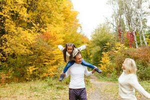 Picture of lovely family in autumn park, young parents with nice adorable daughter playing outdoors, have fun on backyard in fall, happy family enjoy autumnal nature photo