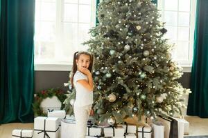 Pretty little girl smiling with present near the Christmas tree photo