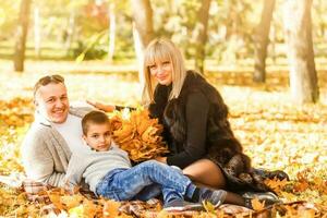 Mom, dad and daughters play in maple leaves pile photo