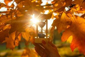 Autumn time theme, Sandglass on fallen leaves in various colors with copy space. photo