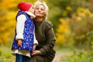 Grandmother and her granddaughter picking berries in the forest photo