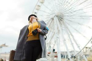 The young girl walks around the city near sights. Ferris wheel. Amusement park. autumn photo