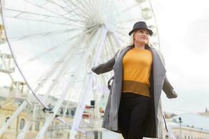 The young girl walks around the city near sights. Ferris wheel. Amusement park. autumn photo