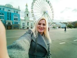 The young girl walks around the city near sights. Ferris wheel. Amusement park. autumn photo