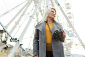 Young woman walking outdoors on the city street near ferris wheel smiling cheerful. photo