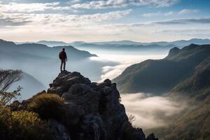 Back view of male manager carrying a suitcase while standing on the hills and looking at misty mountain. Shot at sunrise time photo