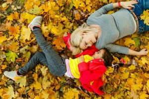 contento familia madre y niño hija jugando y riendo en otoño caminar. foto