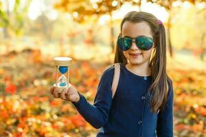 otoño temporada ocio. atmósfera de otoño. adorable sonriente Chica de escuela otoño follaje antecedentes. bueno humor. contento niño. Bienvenido octubre. unido con naturaleza. pequeño niño caminar en otoño parque. foto