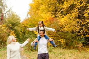 Picture of lovely family in autumn park, young parents with nice adorable daughter playing outdoors, have fun on backyard in fall, happy family enjoy autumnal nature photo