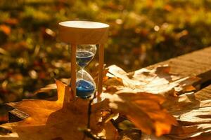 otoño hora tema, reloj de arena en caído hojas en varios colores con Copiar espacio. foto