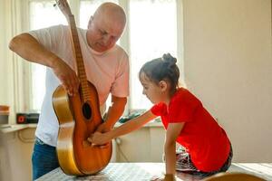 de cerca del hombre mano cambiando instrumentos de cuerda en su antiguo acústico guitarra. foto