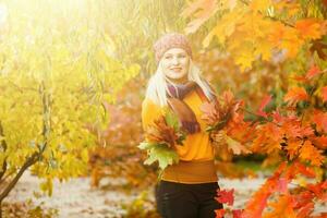 Young woman with autumn leaves in hand and fall yellow maple garden background photo