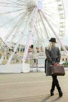 The young girl walks around the city near sights. Ferris wheel. Amusement park. autumn photo